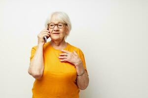 glimlachen ouderen vrouw in een geel t-shirt poseren communicatie door telefoon detailopname emoties foto