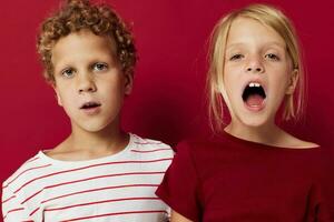 schattig peuter- kinderen emoties staan kant door kant in elke dag kleren rood achtergrond foto