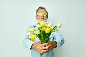 ouderen Mens een boeket van bloemen met bril net zo een geschenk licht achtergrond foto