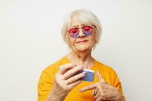 foto van gepensioneerd oud dame in modieus bril met een smartphone in hand- bijgesneden visie