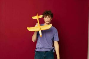jong vent met speelgoed- vliegtuig vermaak rood achtergrond ongewijzigd foto