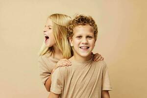 weinig jongen en meisje in beige t-shirts poseren voor pret kinderjaren ongewijzigd foto