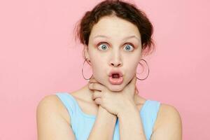 vrouw in blauw t-shirt droes haarzelf emoties roze achtergrond foto