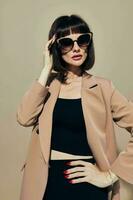 aantrekkelijk vrouw in een beige jasje elegant stijl zonnebril levensstijl ongewijzigd foto
