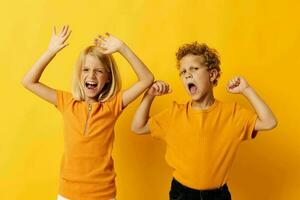 jongen en meisje in geel t-shirts staand kant door kant kinderjaren emoties geel achtergrond foto