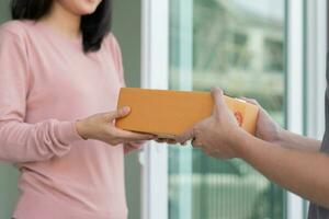 gelukkig glimlachen vrouw ontvangt dozen pakket van koerier in voorkant huis. levering Mens sturen leveren uitdrukken. online winkelen, papier containers, afhalen, postbode, levering onderhoud, pakketjes foto