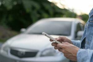 afbreken, gebroken auto, reparatie. Mens toepassingen mobiel telefoon controleren verzekering premies door toepassing ten gevolge naar auto ongeluk . vind garage naar krijgen auto gemaakt gedurende land tour, aan het wachten voor helpen, noodgeval. foto