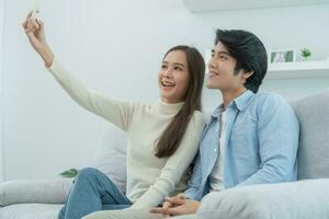 Aziatisch paren zijn genieten van nieuw huis en nemen selfies samen. tiener- man en vrouw na huwelijk. geluk en glimlacht en gelach in warm familie. knuffelen, warm knuffels, tieners eerste liefde foto