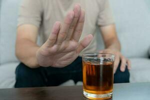 Mens weigert zeggen Nee en vermijden naar drinken een alcohol whisky , stoppen hand- teken mannelijk, alcoholisme behandeling, alcohol verslaving, stoppen drank, hou op drinken alcohol. weigeren glas likeur, ongezond, afwijzen foto