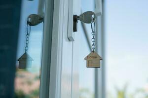 landheer sleutel voor ontgrendelen huis is aangesloten in de deur. tweede hand- huis voor huur en uitverkoop. sleutelhanger is blazen in de wind. hypotheek voor nieuw huis, kopen, verkopen, renoveren, investering, baasje, landgoed foto