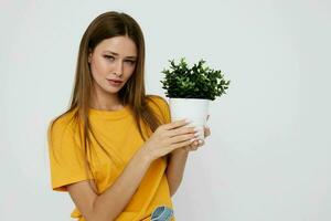 vrolijk meisje in een geel t-shirt bloem in een pot poseren foto