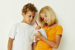 jongen en meisje pret in kleurrijk t-shirts met een kladblok geïsoleerd achtergrond ongewijzigd foto