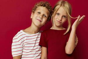 klein kinderen emoties staan kant door kant in elke dag kleren rood achtergrond ongewijzigd foto