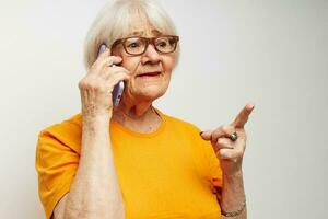 ouderen vrouw in een geel t-shirt poseren communicatie door telefoon licht achtergrond foto