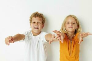 twee blij kinderen poseren hand- gebaar glimlach gewoontjes slijtage licht achtergrond foto