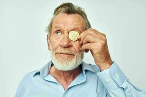 senior grijs haar Mens in een blauw overhemd bitcoins Aan de gezicht geïsoleerd achtergrond foto