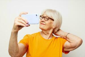 glimlachen ouderen vrouw in gewoontjes t-shirt zonnebril pratend Aan de telefoon bijgesneden visie foto
