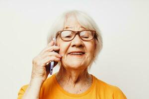 glimlachen ouderen vrouw in gewoontjes t-shirt zonnebril pratend Aan de telefoon bijgesneden visie foto