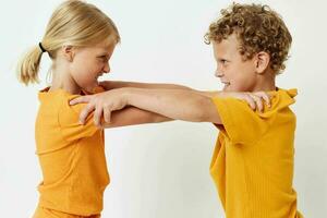 twee blij kinderen in geel t-shirts staand kant door kant kinderjaren emoties licht achtergrond ongewijzigd foto