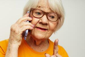 ouderen vrouw in gewoontjes t-shirt zonnebril pratend Aan de telefoon licht achtergrond foto