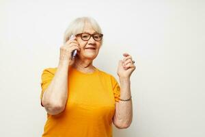 foto van gepensioneerd oud dame in een geel t-shirt poseren communicatie door telefoon bijgesneden visie