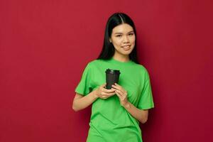 charmant jong Aziatisch vrouw in een groen t-shirt een glas van drinken pret studio model- ongewijzigd foto