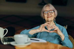 senior vrouw zittend in een cafe met een kop van koffie en een laptop gepensioneerd vrouw chatten ongewijzigd foto