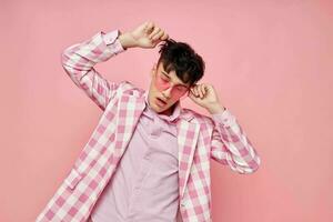 een jong Mens roze bril geruit jasje mode poseren roze achtergrond ongewijzigd foto