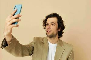 Mens in een pak poseren emoties op zoek Bij de telefoon beige achtergrond foto