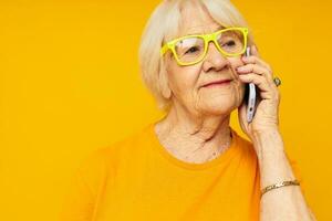 ouderen vrouw gelukkig levensstijl in geel t-shirts met telefoon geel achtergrond foto