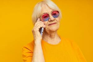 glimlachen ouderen vrouw gelukkig levensstijl in geel t-shirts met telefoon detailopname emoties foto