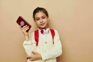 weinig meisje met telefoon poseren rood rugzak kinderjaren ongewijzigd foto