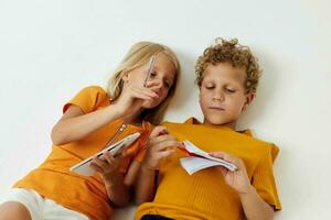 portret van schattig liggen Aan de verdieping met blocnotes en potloden geïsoleerd achtergrond ongewijzigd foto