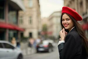 mode vrouw glimlach met tanden staand Aan de straat in voorkant van de stad toerist in elegant kleren met rood lippen en rood baret, reis, filmische kleur, retro wijnoogst stijl, stedelijk mode. foto