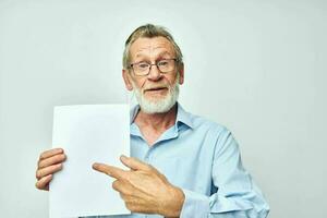 portret van gelukkig senior Mens in een blauw overhemd en bril een wit vel van papier bijgesneden visie foto