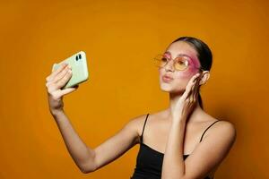 portret van mooi jong vrouw looks Bij de telefoon helder bedenken poseren mode emoties geel achtergrond ongewijzigd foto