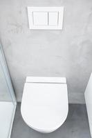 aan de muur gemonteerd of hangend toilet of wc in de badkamer van het huis met drukknop doorspoelen foto