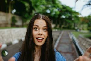 portret van een vrouw brunette glimlach met tanden wandelen buiten tegen een backdrop van palm bomen in de tropen, zomer vakanties en buitenshuis recreatie, de zorgeloos levensstijl van een freelance leerling. foto