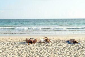 niet geïdentificeerd toeristen aan het liegen naar beneden naar genieten zonnen Bij Karon strand in phuket van Thailand. foto