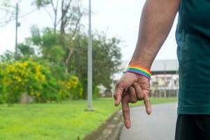 hand- vervelend regenboog of lgbtq symbool polsbandje uitrekken naar beneden met liefde symbool naar campagne voor bescherming en ondersteuning Aan geslacht verscheidenheid of lgbtq mensen en gemeenschap foto