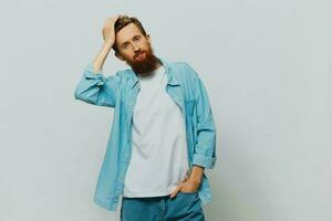 mannetje hipster portret glimlach Aan grijs achtergrond in blauw overhemd en wit t-shirt, portret van een Mens met een baard foto