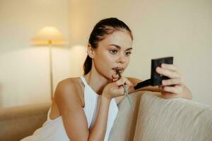 een vrouw Bij huis looks in de spiegel en is van toepassing bedenken lippenstift, schoonheid concept, probleem huid zorg met acne, huis verzinnen. foto