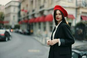 mode vrouw portret staand Aan de straat in voorkant van de stad in elegant kleren met rood lippen en rood baret, reis, filmische kleur, retro wijnoogst stijl, stedelijk mode levensstijl. foto