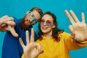 een vrouw en een Mens pret paar aanzwengelen en tonen tekens met hun handen glimlachen vrolijk, Aan een blauw achtergrond, de concept van een echt verhouding in een familie. foto