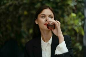 vrouw met rood lippen glimlach met tanden drinken thee in een cafe van een Turks glas mok Aan de straat, zomer reis, vakantie in de stad foto