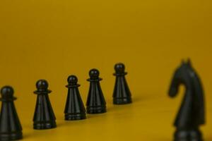 een zwart paard schaak staand voor geconfronteerd naar de team en vechten de probleem Aan bedrijf Aan geïsoleerd geel achtergrond, gebruikt voor succes en strategie concept foto