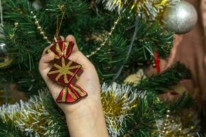 een kind jurken omhoog een Kerstmis boom met speelgoed foto