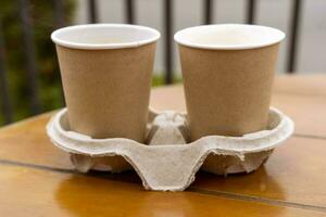 papier cups met koffie Aan de tafel van een buitenshuis cafe. meenemen voedsel. foto