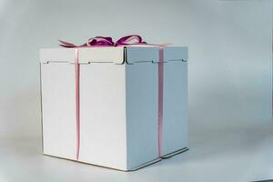 groot wit geschenk doos gebonden met een rood lint Aan een wit achtergrond foto
