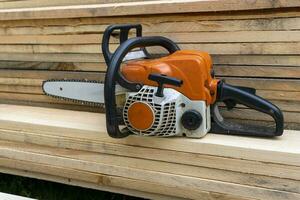 portable benzine keten zag Aan een stack van houten planken. foto